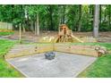 Landscaped backyard with wood retaining walls, a concrete patio, and a custom-built wooden playset with a slide at 998 Pointer Rdg, Tucker, GA 30084