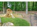 Wooden playset and a swing with a slide for outdoor enjoyment in a green, tree-filled backyard at 998 Pointer Rdg, Tucker, GA 30084