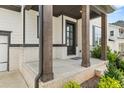 Inviting front porch with brick accents, wooden columns, and a stylish black front door at 382 Tillman Pass, Woodstock, GA 30188