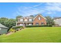 Charming brick home featuring a well-maintained lawn and manicured hedges beneath a clear blue sky at 5821 Saint Miles Drive Dr, Buford, GA 30518