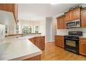 Cozy kitchen with wooden cabinets, granite countertops, black appliances, and a view of the breakfast nook at 5821 Saint Miles Drive Dr, Buford, GA 30518