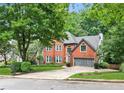 Two-story brick home featuring a manicured lawn, mature landscaping, and attached two-car garage at 2220 Cape Courage Way, Suwanee, GA 30024