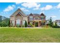 Charming stone home featuring an expansive lawn, manicured landscaping, and a welcoming front entrance at 1835 Henley Way, Alpharetta, GA 30009