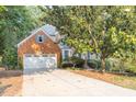 A traditional brick home featuring an attached two-car garage, driveway and mature trees at 1253 Rivermark Ct, Lawrenceville, GA 30043