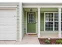 A close-up of the home's entrance, with a green door, white trim, and manicured landscaping at 186 Wallnut Hall Cir, Woodstock, GA 30189