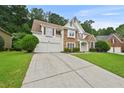 Beautiful home with stone details, a manicured lawn, and a long driveway leading to a two-car garage at 4360 Canterbury Walk Dr, Duluth, GA 30097