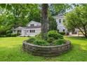 Scenic backyard with a stone-lined garden bed, lush green lawn, and mature trees at 6771 Sunny Brook Ln, Atlanta, GA 30328