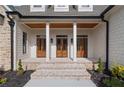Inviting entrance featuring triple wood doors, white columns, and brick steps at 100 Percheron Dr, Canton, GA 30114