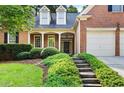 Brick home featuring a covered porch, stone steps, and well-maintained landscaping leading to the front door at 795 Lake Medlock Dr, Alpharetta, GA 30022