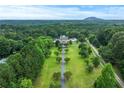 An aerial view shows this grand home centered on a vast manicured lawn, with the home accessed by a long private driveway at 2595 Ross Rd, Snellville, GA 30039