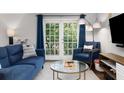 Bright living room with a comfortable blue sofa, armchair, and access to a private balcony at 1150 Collier Nw Rd # L14, Atlanta, GA 30318