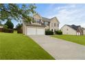 Traditional home with two-car garage and driveway, surrounded by a green lawn and mature trees at 165 Heaton Place Trl, Covington, GA 30016
