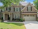 Brick home with an attached two car garage, front yard, and covered front porch at 1450 Liberty Ln, Cumming, GA 30040