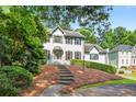 Beautiful home with a manicured lawn, mature trees, and a charming covered entryway leading to the front door at 3185 Country Club Nw Ct, Kennesaw, GA 30144