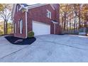 Side view of the house featuring a two-car garage and a well-kept driveway at 2001 Towne Lake W Hls, Woodstock, GA 30189