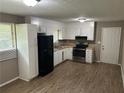 Kitchen features black appliances, white cabinets and laminate flooring at 8415 Magnolia Dr, Jonesboro, GA 30238