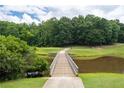 Beautiful golf course view from a wooden bridge over a pond surrounded by lush greenery at 3525 Stone Cliff Way, Woodstock, GA 30189