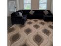 Living room featuring a large black sectional sofa on a patterned rug at 3378 English Elm Way, Loganville, GA 30052