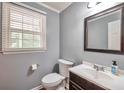 Cozy half bathroom features a modern vanity, mirror, and a window with natural light at 2165 Shillings Chase Nw Dr, Kennesaw, GA 30152