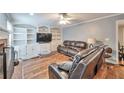 Comfortable living room boasts custom built-ins, a ceiling fan, and cozy brown leather furniture for relaxation at 2165 Shillings Chase Nw Dr, Kennesaw, GA 30152