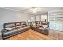 Spacious living area with sleek hardwood floors, a ceiling fan, and stylish brown leather seating at 2165 Shillings Chase Nw Dr, Kennesaw, GA 30152