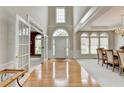 Elegant foyer showcasing hardwood floors, high ceilings, arched windows, and an open view into the dining room at 5357 Harbury Cv, Suwanee, GA 30024