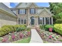 Charming home featuring blooming flowers, lush bushes, and a welcoming walkway leading to the front door at 5357 Harbury Cv, Suwanee, GA 30024