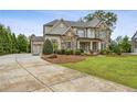 Elegant two-story home with stone and siding exterior, concrete driveway, and manicured lawn at 10 Nesbit Reserve Ct, Atlanta, GA 30350