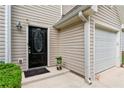 Close-up showcasing the front door and garage of a tan home with dark shutters and manicured landscaping at 248 Springbottom Dr, Lawrenceville, GA 30046