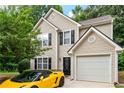 Charming two-story home showcasing a tan exterior, black shutters and a yellow luxury car parked in the driveway at 248 Springbottom Dr, Lawrenceville, GA 30046