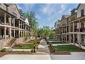 View of townhomes with a central walkway surrounded by greenery, trees and manicured lawns at 160 Chiswick Cir # 2, Alpharetta, GA 30009