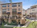 Beautiful three-story brick townhome with balconies, a well-kept lawn, and a staircase at 6838 Prelude Dr, Atlanta, GA 30328