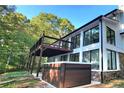 A modern home's exterior with a deck, hot tub, and large windows, surrounded by a lush green forest at 2900 Orchard Sw Rd, Conyers, GA 30094