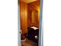 Cozy powder room featuring classic wood paneling, a vintage vanity, and a compact toilet for efficient use of space at 1026 Riverbend Club Se Dr, Atlanta, GA 30339