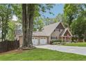 View of a home's exterior, showing the garage, front yard, and mature trees around the property at 890 Lake Dr, Snellville, GA 30039