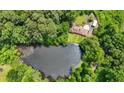 Overhead view of a secluded property featuring a home and a tranquil pond surrounded by a dense forest at 347 Oakhurst Dr, Marietta, GA 30066
