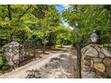 Close-up of a gated driveway with decorative stone pillars and lush greenery at 11270 Stroup Road, Roswell, GA 30075