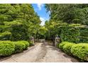 Private driveway entrance with lush greenery, stone pillars, and mature trees at 11270 Stroup Road, Roswell, GA 30075