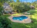 Aerial view of the kidney-shaped pool surrounded by lush green landscaping and backyard amenities at 2390 Sassafrass Ln, Powder Springs, GA 30127