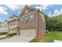 Side view of a brick townhome with manicured lawn, showcasing the attached two-car garage and neat landscaping at 3255 Clear View Dr, Snellville, GA 30078