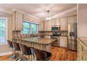 Bright kitchen featuring granite countertops, stainless steel appliances and counter seating on hardwood flooring at 4655 Barnes Ct, Loganville, GA 30052