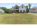 Beautiful home featuring stone accents, a covered porch, lush landscaping, and a well-manicured lawn at 2855 Pilgrim Mill, Cumming, GA 30041