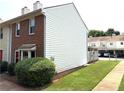 Side view of a two-story townhome, showcasing the neatly maintained lawn and adjacent covered parking area at 210 Mill Creek Pl, Roswell, GA 30076