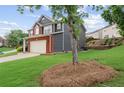 Two-story home with gray siding, brick facade, two-car garage, and spacious front lawn at 1657 Bradmere Ln, Lithia Springs, GA 30122