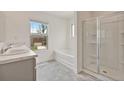 Bright bathroom featuring double sinks, a separate tub, and a glass shower at 4117 Flat Rock Pt, Stonecrest, GA 30038