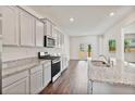 Modern kitchen with white cabinetry, granite countertops, stainless steel appliances, and hardwood floors at 4117 Flat Rock Pt, Stonecrest, GA 30038