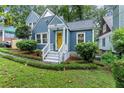 Attractive blue home featuring white trim, a cheerful yellow door, and lush green landscaping at 233 Spence Se Ave, Atlanta, GA 30317