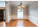 Spacious dining room with hardwood floors, chandelier, wainscoting, and large arched window for natural light at 185 Beracah Sw Walk, Atlanta, GA 30331