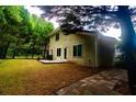 Spacious backyard featuring a stone-paved walkway, well-maintained lawn, and lush, mature trees at 128 Garden Walk, Stockbridge, GA 30281