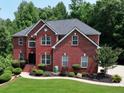 Charming red brick home featuring an attached garage, landscaped yard, and lush greenery at 2725 Bailey Ne Pl, Conyers, GA 30013